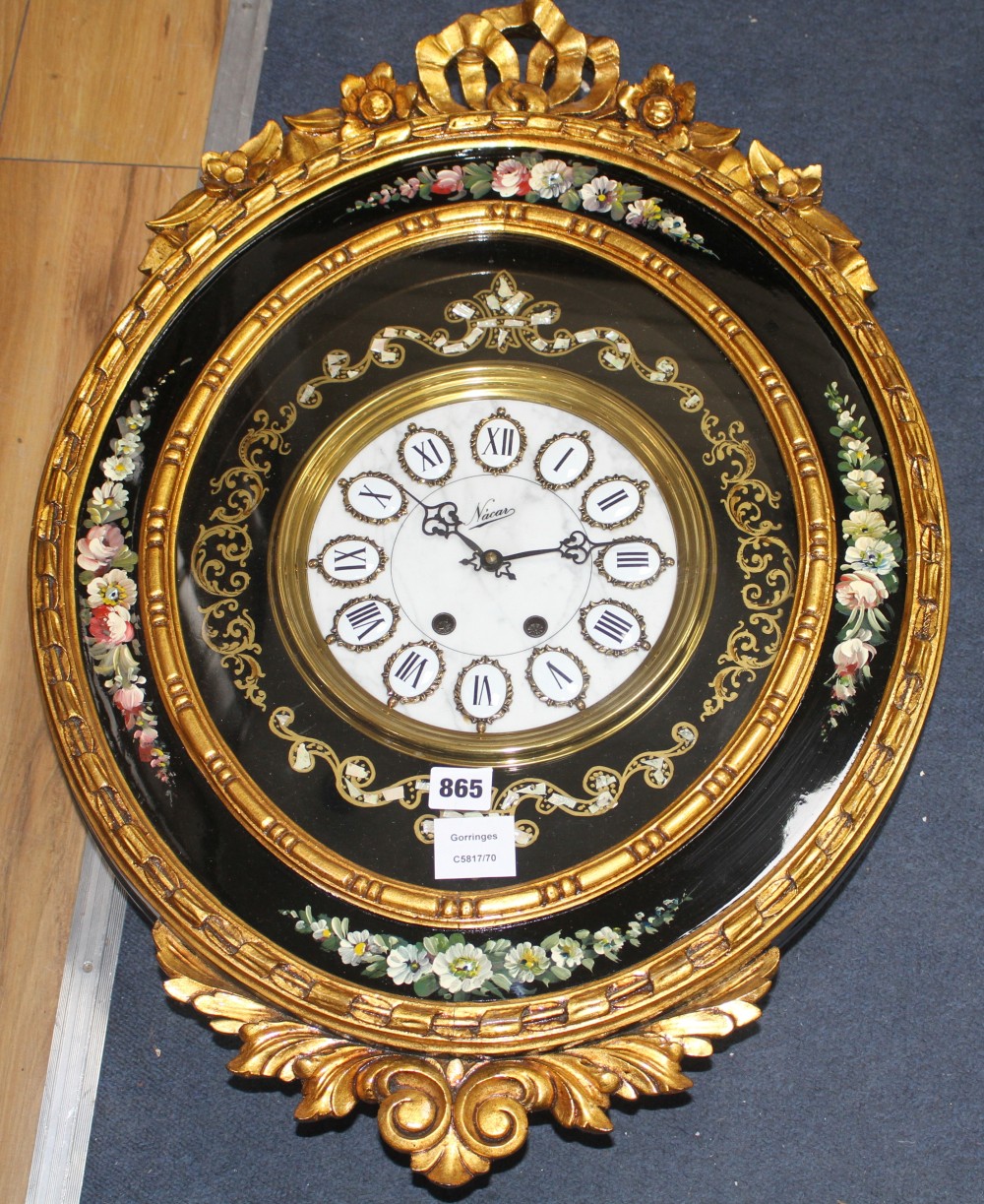 An ornate gold and floral painted oval wall clock, the dial signed Nacar, W.48cm H.68cm